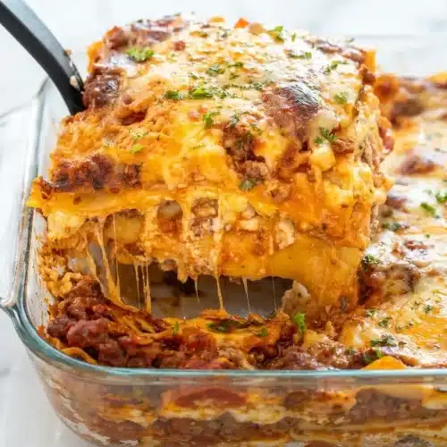 Slice of Classic Beef Lasagna featuring umami sausage meat sauce and a creamy nutmeg-spiced ricotta filling.