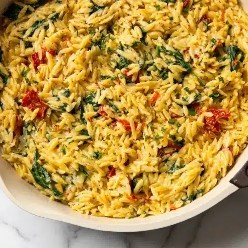 Creamy Boursin Orzo Bake in a skillet with golden edges from a two-stage flavor-boost bake, topped with sun-dried tomatoes.