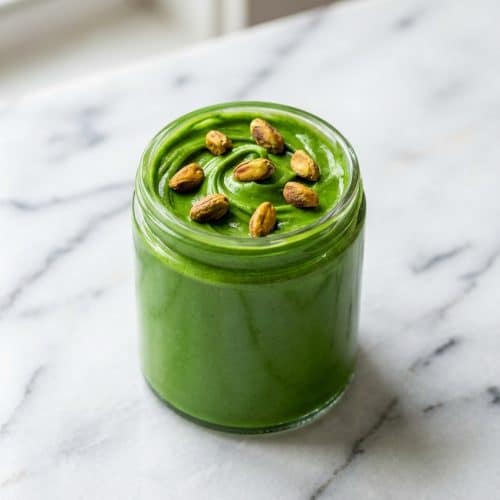 Spoonful of vibrant green pistachio butter recipe showing a smooth, emulsified texture created by the blanch-then-toast method.