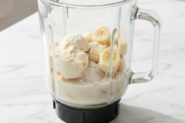 A tall glass of a creamy vanilla protein shake recipe, made extra thick with cauliflower and topped with a banana slice.