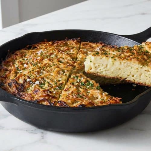 Sliced serving of this potato kugel recipe showing a golden crispy crust achieved by a cast-iron sear and boiling water pour.
