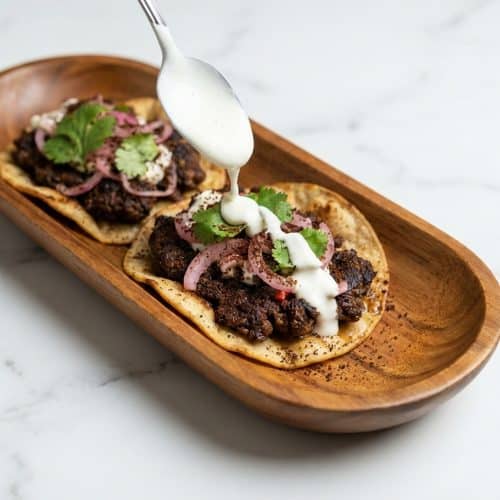 Dubai Tacos recipe featuring Turkish coffee infused ground lamb on a griddle with bright pickled red onions.