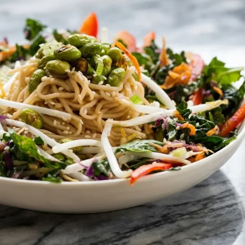 Colorful edamame rice noodle salad featuring charred blistered edamame and savory smacked cucumbers in a large bowl.