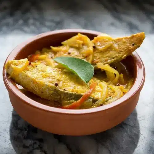Creamy fish molly kerala recipe with rice flour-coated fish and a fresh virgin coconut oil finish in a claypot.