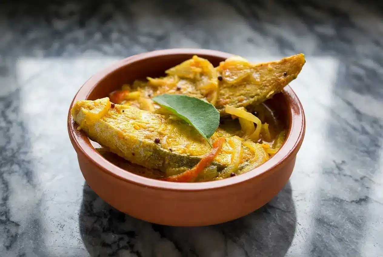 Creamy fish molly kerala recipe with rice flour-coated fish and a fresh virgin coconut oil finish in a claypot.