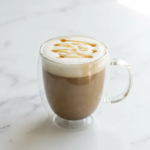 A warm hojicha latte recipe served in a ceramic mug, featuring the salted maple enhancement with a light, frothy top.