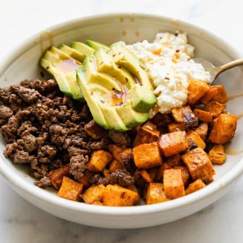 Hot Honey Ground Beef Bowls topped with chili-lime pepitas, creamy avocado, and roasted sweet potatoes.