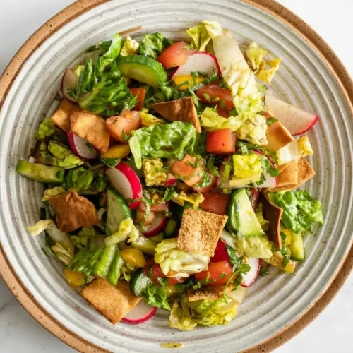 Colorful lebanese fattoush salad recipe in a bowl, topped with crispy garlic za'atar pan-fried pita chips and fresh mint.