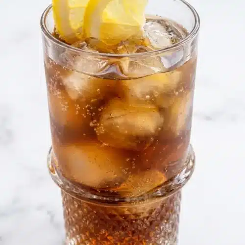 A glass mug of the Lemon Balm Recipe for Weight Loss featuring a golden herbal infusion, fresh ginger slices, and raw ACV.