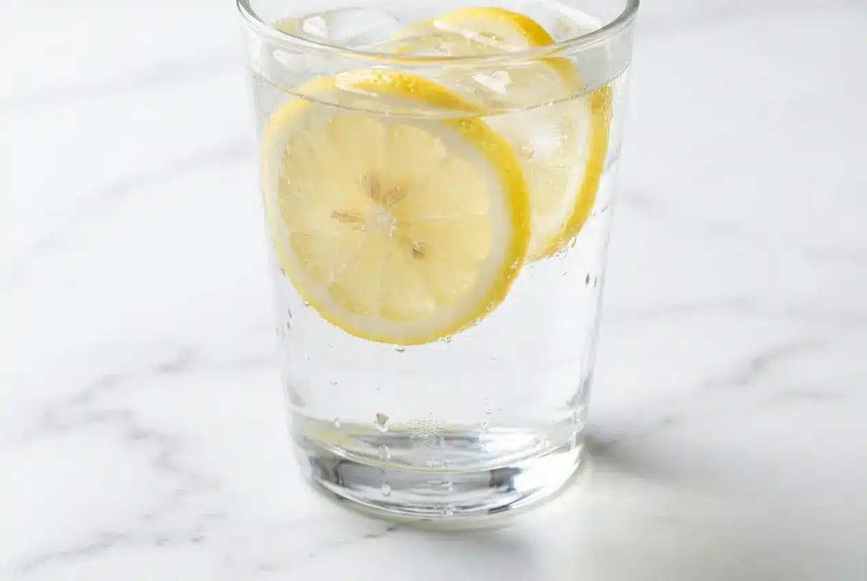A refreshing glass of this Lemon Water Recipe, showing fresh lemon slices muddled with a tiny pinch of Himalayan pink salt.