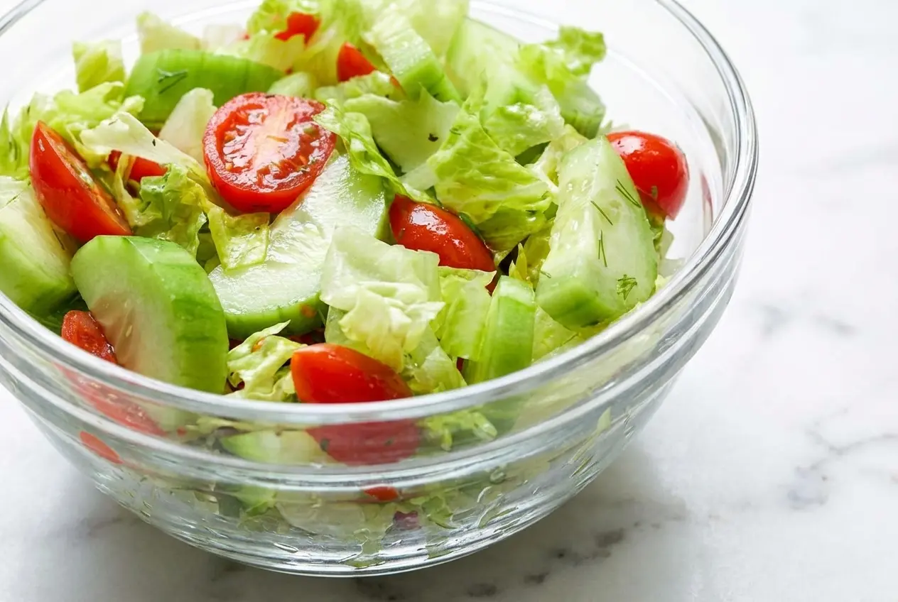 A fresh bowl of lettuce tomato and cucumber salad tossed in a vibrant tomato-juice vinaigrette with red wine vinegar.