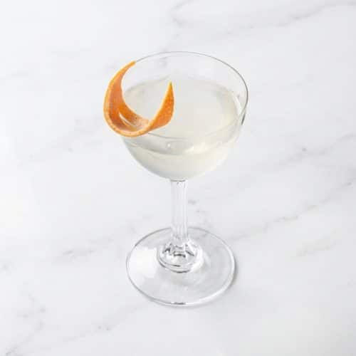 London Calling cocktail in a coupe glass with a vibrant grapefruit zest twist and potent Navy Strength gin notes.