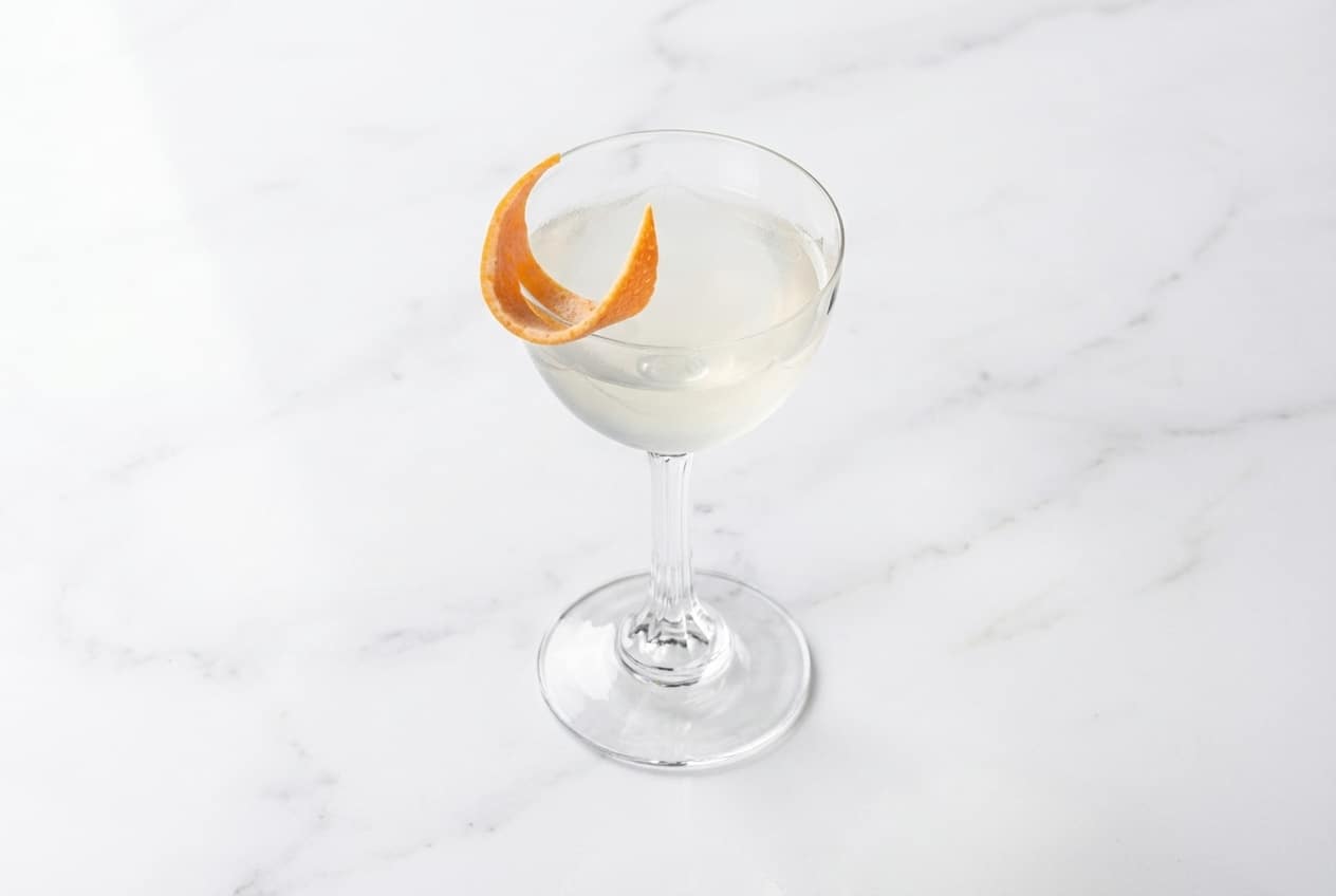 London Calling cocktail in a coupe glass with a vibrant grapefruit zest twist and potent Navy Strength gin notes.