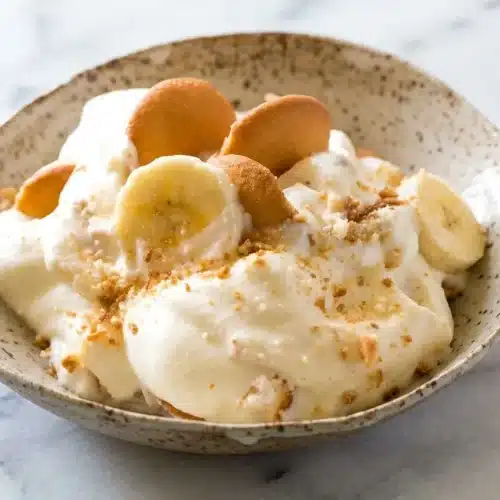 Layered Magnolia Bakery’s Banana Pudding with toasted salted wafers and vanilla bean cream in a glass bowl.