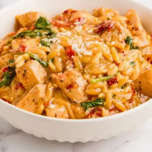 Skillet of marry me chicken orzo recipe with sun-dried tomatoes, spinach, and a rich white wine deglazed cream sauce.