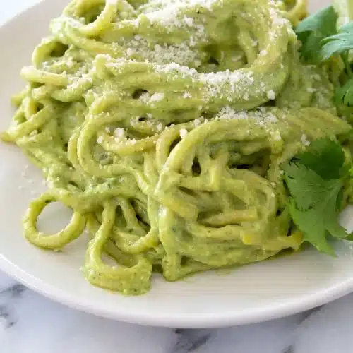 Bowl of Mexican green spaghetti recipe with roasted garlic and poblano cream sauce, finished with a squeeze of fresh lime.