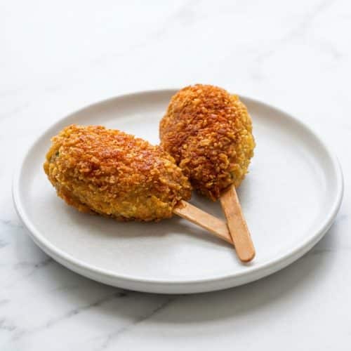 Crispy mock chicken legs coated in brown butter toasted cornflake crumbs, seasoned with smoked paprika on a rustic platter.
