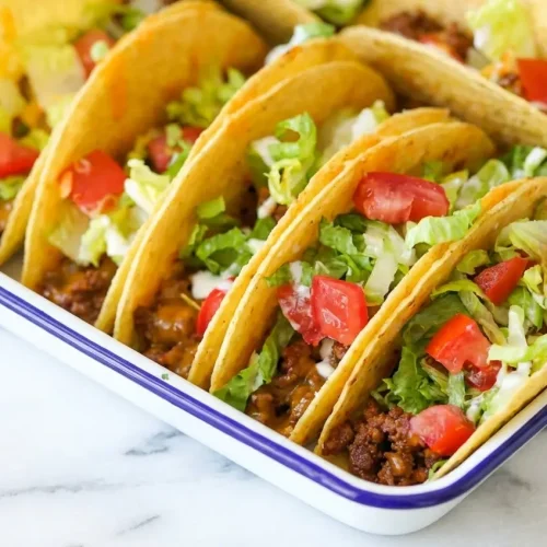 Oven Baked Cheesy Tacos in a casserole dish, featuring perfectly crispy shells thanks to a refried bean and cheese barrier.