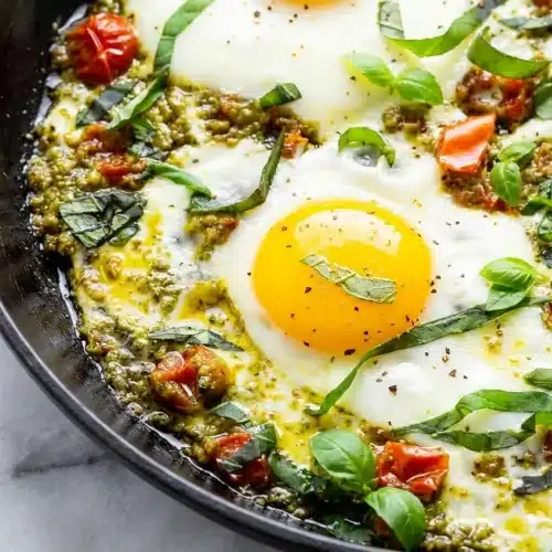 Sunny side up Pesto Eggs Recipe with a crispy feta skirt and hot honey drizzle served over toasted sourdough.