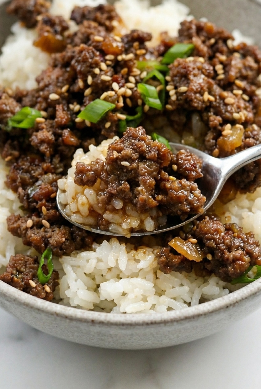 Close-up of Ground Beef Bulgogi Bowls topped with vibrant kimchi and toasted sesame seeds.