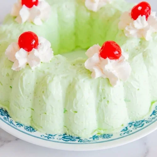 A slice of Retro Sea Foam Salad Recipe featuring toasted chopped pecans, cream cheese with vanilla, and mashed pears in a mold.