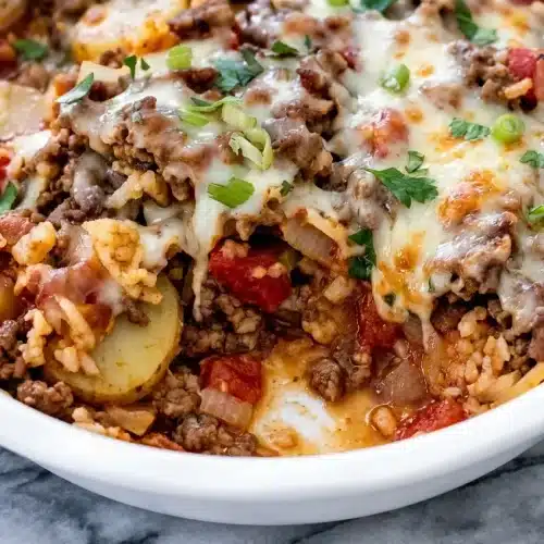 Layered Shipwreck Casserole in a baking dish showing the rich, umami-boosted deglaze over ground beef and potatoes.