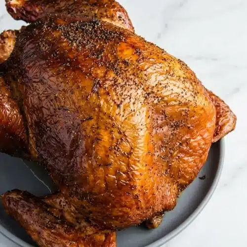 Spatchcocked smoked turkey with crispy golden brown skin from a baking powder dry brine, served on a cutting board.
