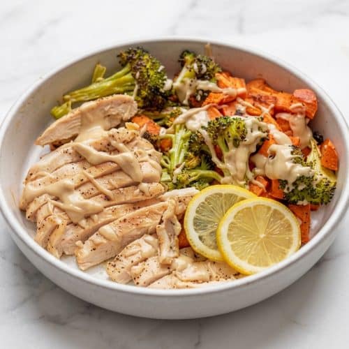 A vibrant tahini chicken bowl with roasted sweet potatoes and broccoli, drizzled with a creamy dressing made from a tahini-lemon paste.