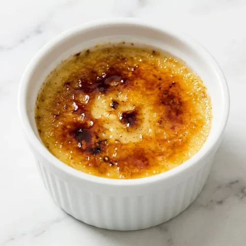 Ramekin of Tahitian Vanilla Creme Brulee featuring a crispy caramelized sugar crust over cold-infused 24-hour steeped custard.