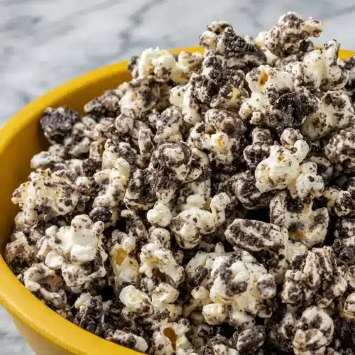Bowl of cookies cream popcorn drizzled with vanilla bean salted white chocolate and crushed sandwich cookies.