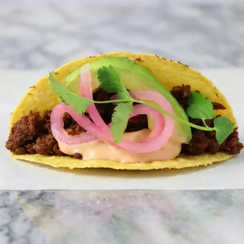 Vegan chipotle beef tacos featuring lime-deglazed plant-based meat topped with bright pickled onions.