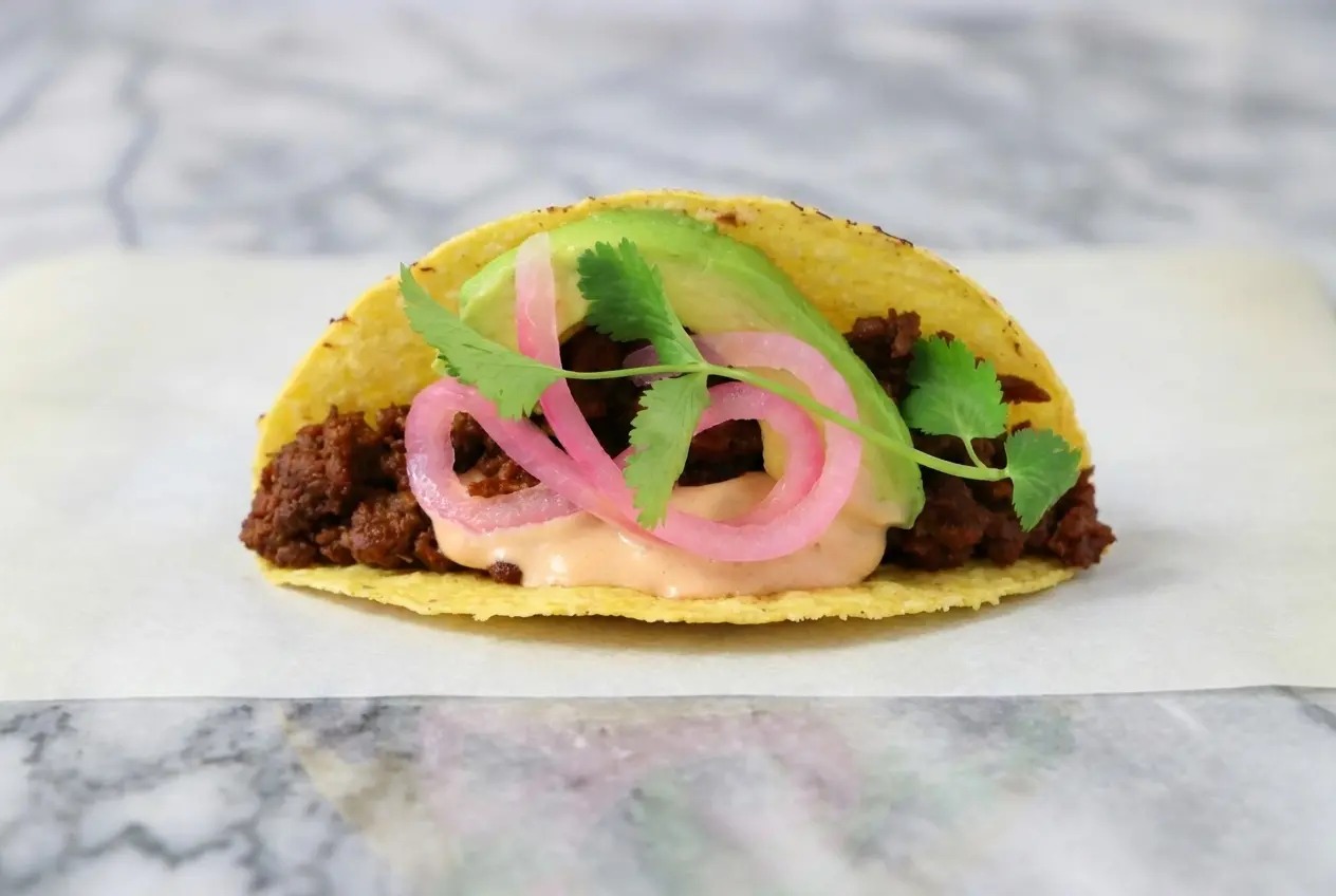 Vegan chipotle beef tacos featuring lime-deglazed plant-based meat topped with bright pickled onions.