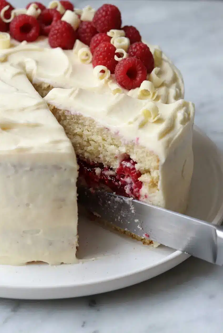 Spreading tart raspberry compote over a White Chocolate Raspberry Cake layer with an offset spatula.