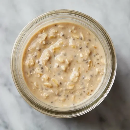 A mason jar of creamy brown sugar overnight oats, topped with a sprinkle of toasted oats for extra flavor and a satisfying texture.
