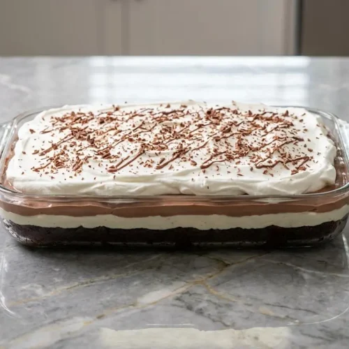 A square slice of Brownie Refrigerator Cake on a white plate, showing its rich layers and deep color from the espresso-infused chocolate.