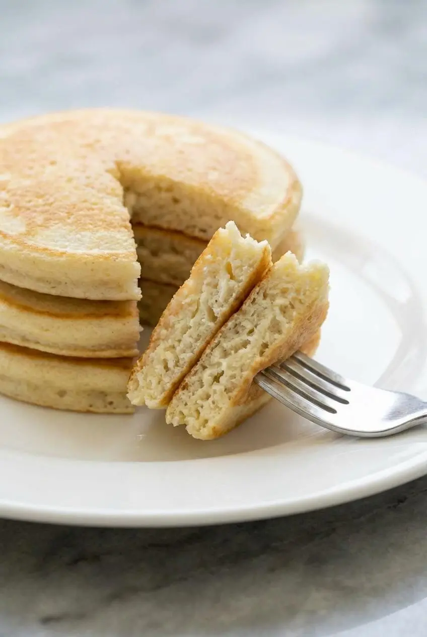 A close-up shot of a Greek yogurt pancake cut open, revealing the incredibly light and fluffy interior texture.