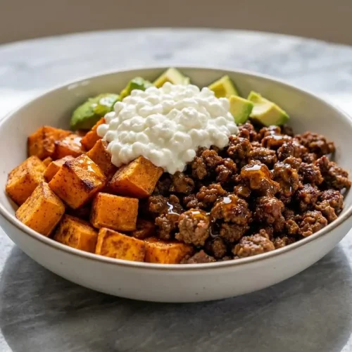 A hot honey cottage cheese sweet potato beef bowl with paprika-seared ground beef, creamy avocado, and roasted sweet potatoes.