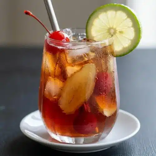 A tall glass of refreshing Cherry Ginger Iced Tea with a vibrant ruby color, filled with ice cubes and garnished with a lime wedge.
