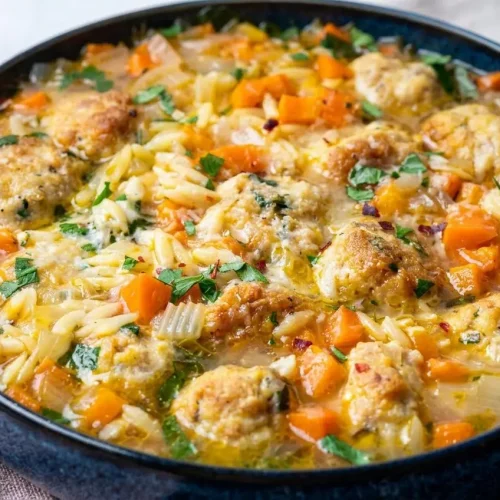 A comforting bowl of chicken meatball soup with tender meatballs, orzo, and vegetables in a savory Parmesan broth.