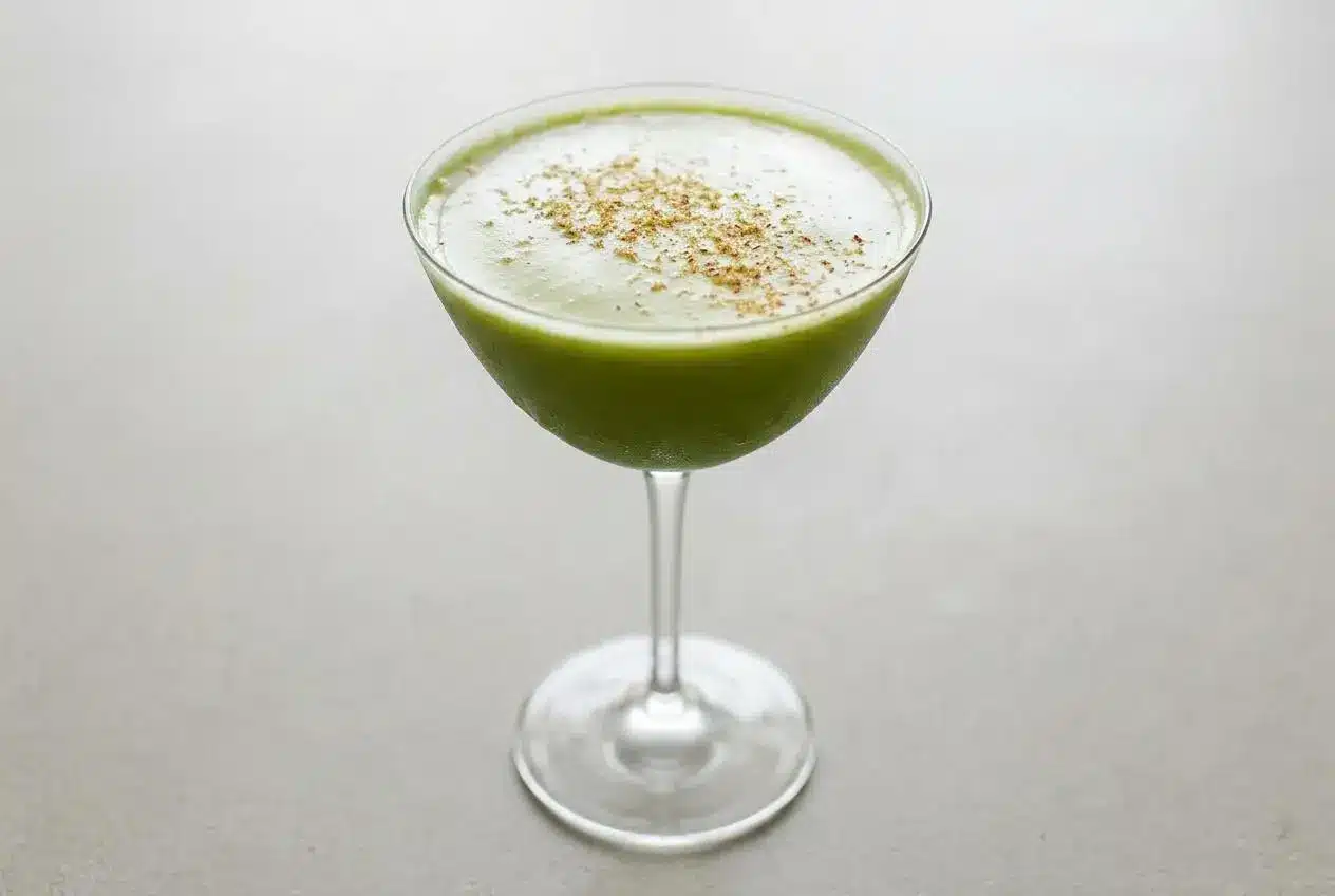 A creamy Matchatini cocktail in a coupe glass, garnished with a sprinkle of fresh nutmeg.