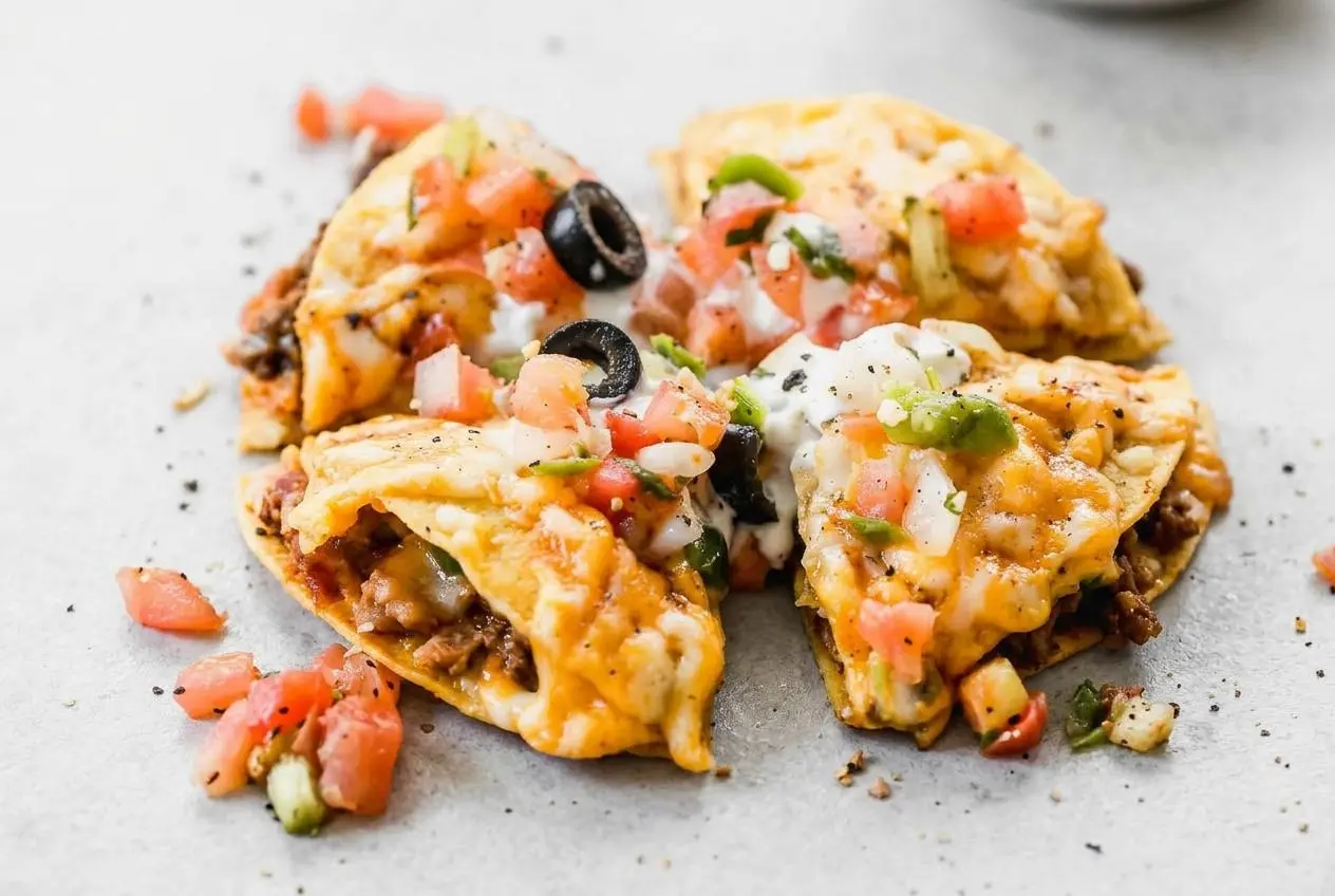 A finished Mexican pizza with crispy tortilla layers, seasoned beef, and a golden, bubbly melted cheese topping.