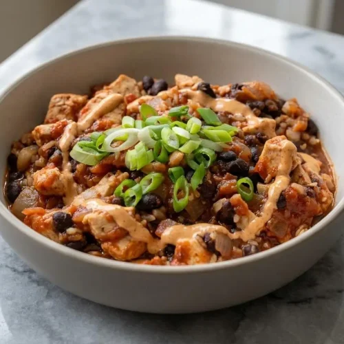 A vibrant high protein chicken burrito bowl with cilantro lime rice, corn salsa, black beans, and a generous drizzle of smoky chipotle crema.