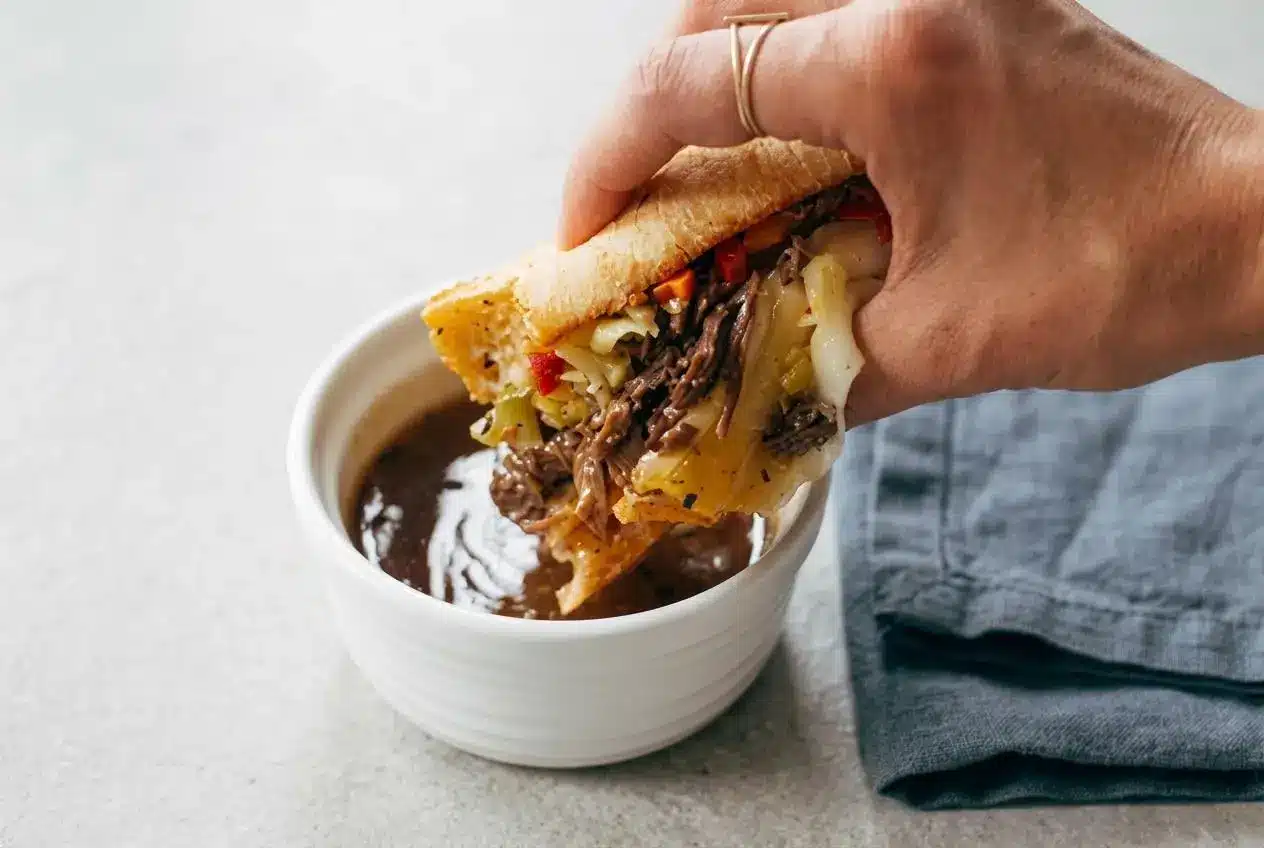 An Instant Pot Italian Beef sandwich on a crusty hoagie roll, overflowing with tender shredded beef, melted provolone, and giardiniera.