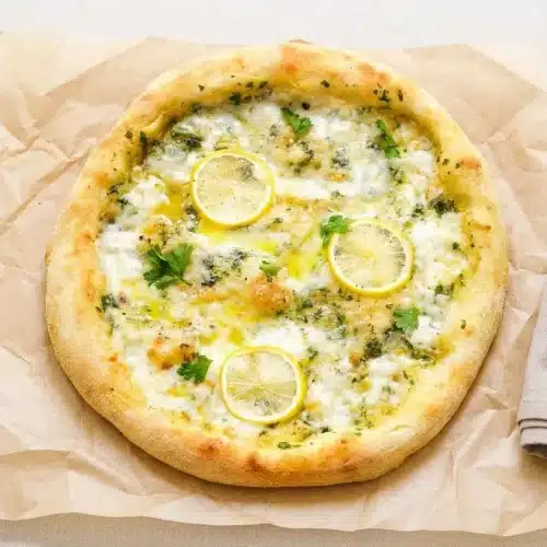 A rectangular lemon pizza fresh from the oven, with bubbly melted mozzarella, fresh parsley, and a golden-brown crust.