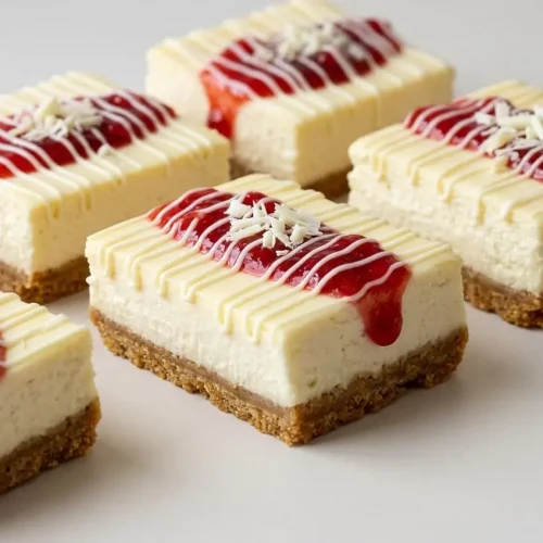 A sliceable Philadelphia Cheesecake Bars with a buttery graham cracker crust, creamy filling, strawberry compote, and a white chocolate