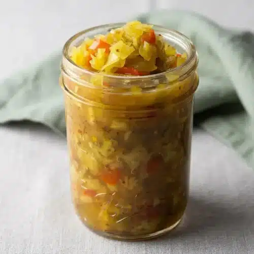 A glass bowl filled with sweet and tangy chow chow recipe, showing the finely chopped green tomatoes, cabbage, and peppers in a glossy