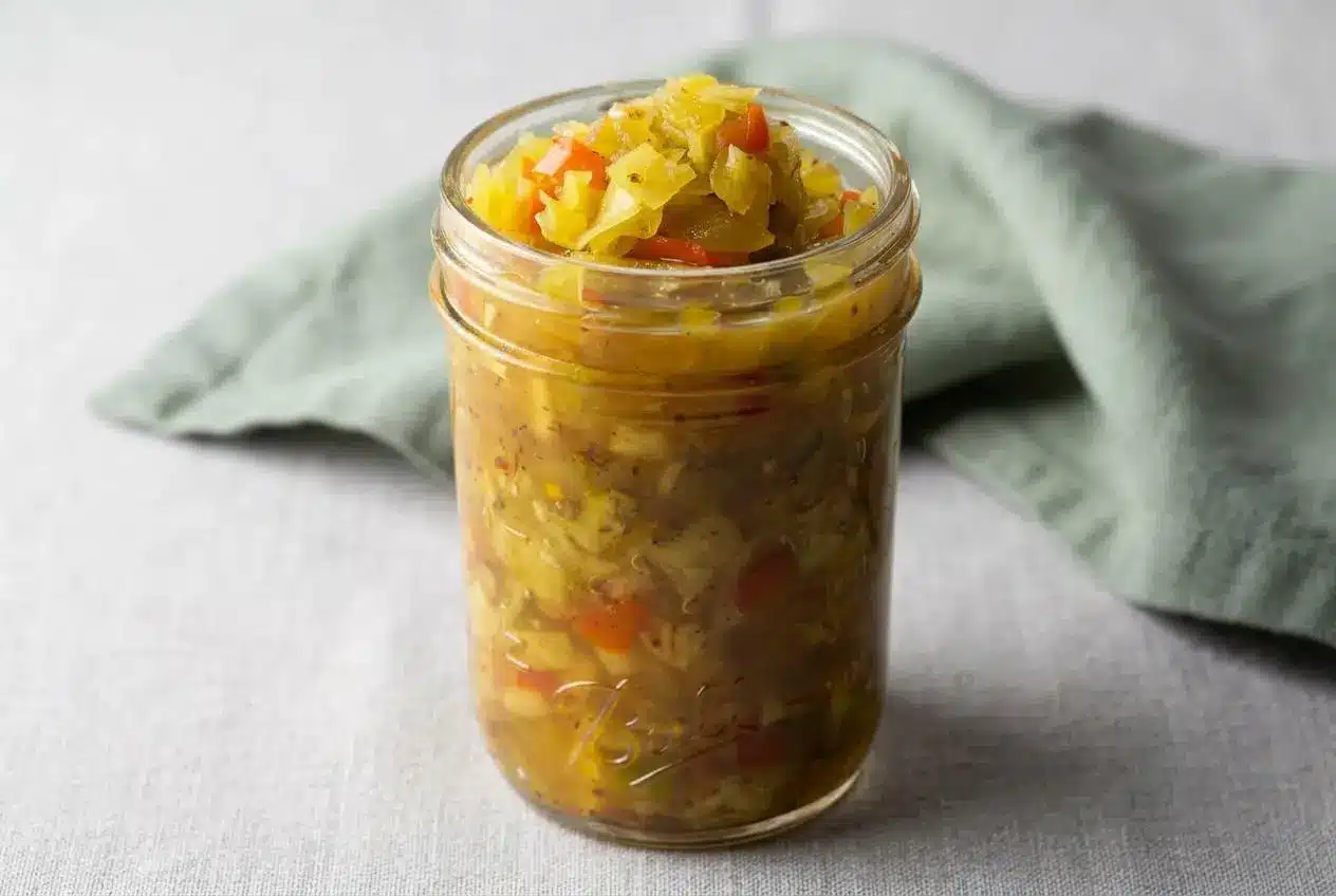 A glass bowl filled with sweet and tangy chow chow recipe, showing the finely chopped green tomatoes, cabbage, and peppers in a glossy