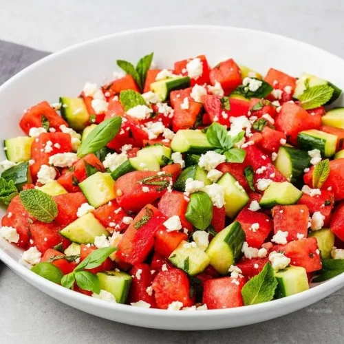 Watermelon Feta Salad in a white serving bowl, showing juicy red watermelon cubes, creamy feta crumbles, and fresh green herbs.