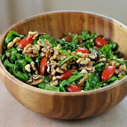 Arugula Salad with Feta in a white bowl, showing fresh peppery greens, halved grape tomatoes, walnuts, and chunks of creamy feta cheese.
