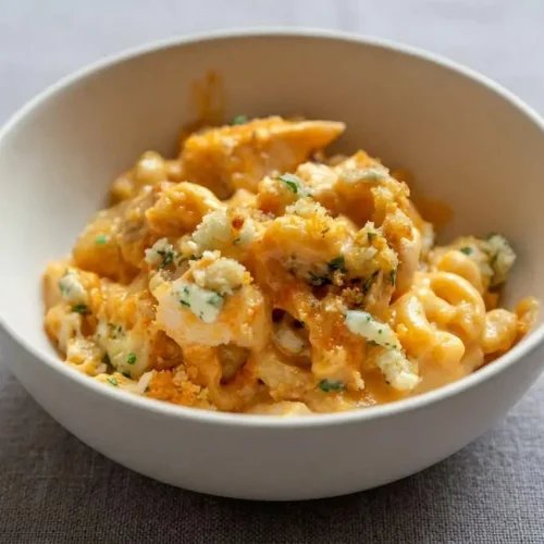 A rectangular white casserole dish of baked Buffalo Chicken Mac and Cheese with a golden panko and blue cheese topping.